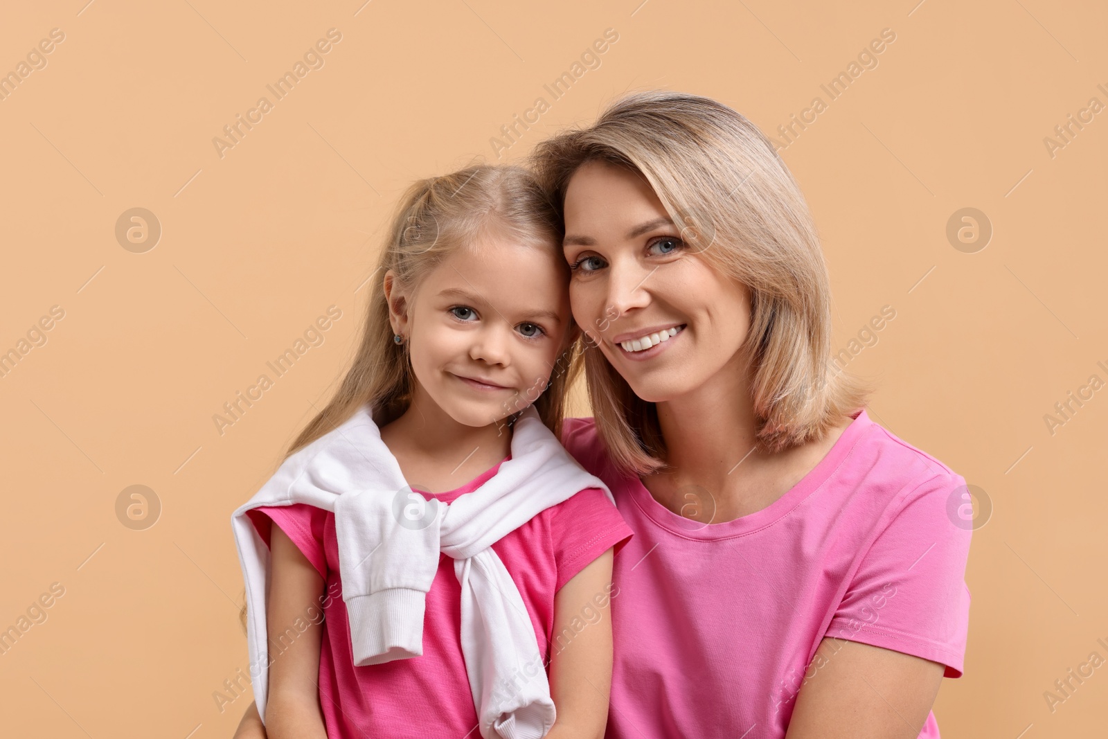 Photo of Cute little girl with her mom on beige background. Happy Mother's Day