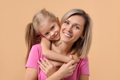 Cute little girl hugging her mom on beige background. Happy Mother's Day