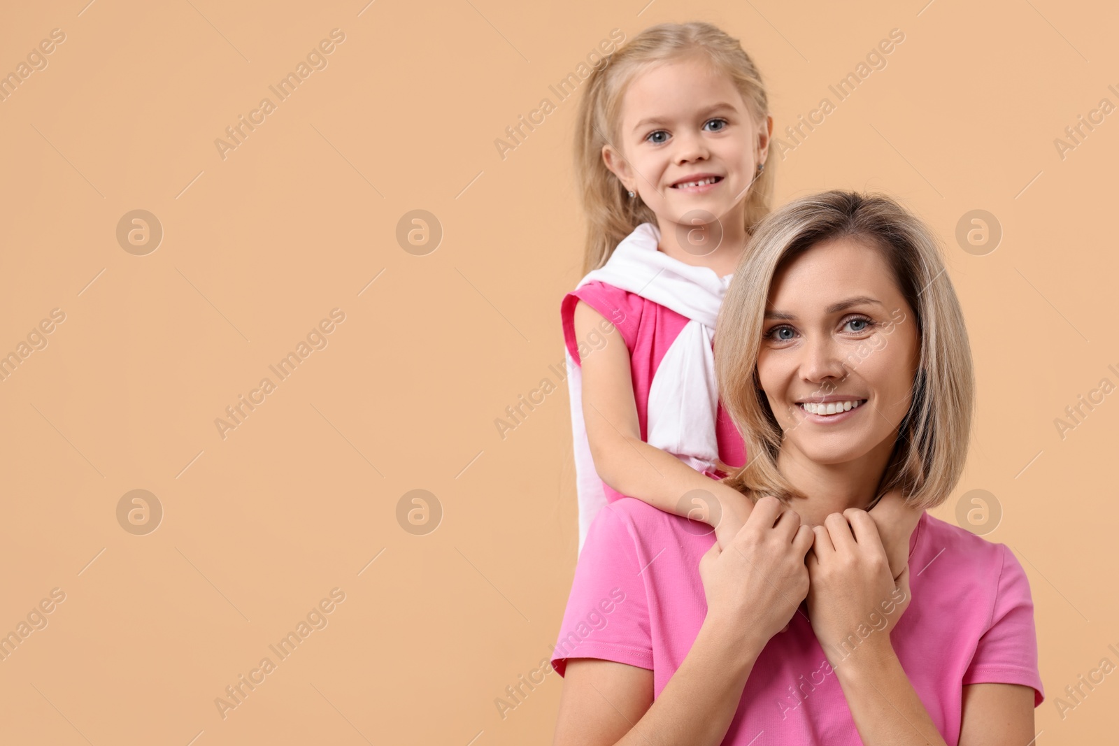 Photo of Cute little girl with her mom on beige background, space for text. Happy Mother's Day