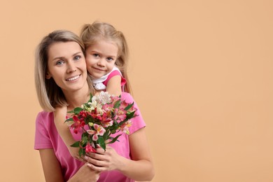 Photo of Happy woman with her daughter and bouquet of alstroemeria flowers on beige background, space for text. Mother's Day celebration