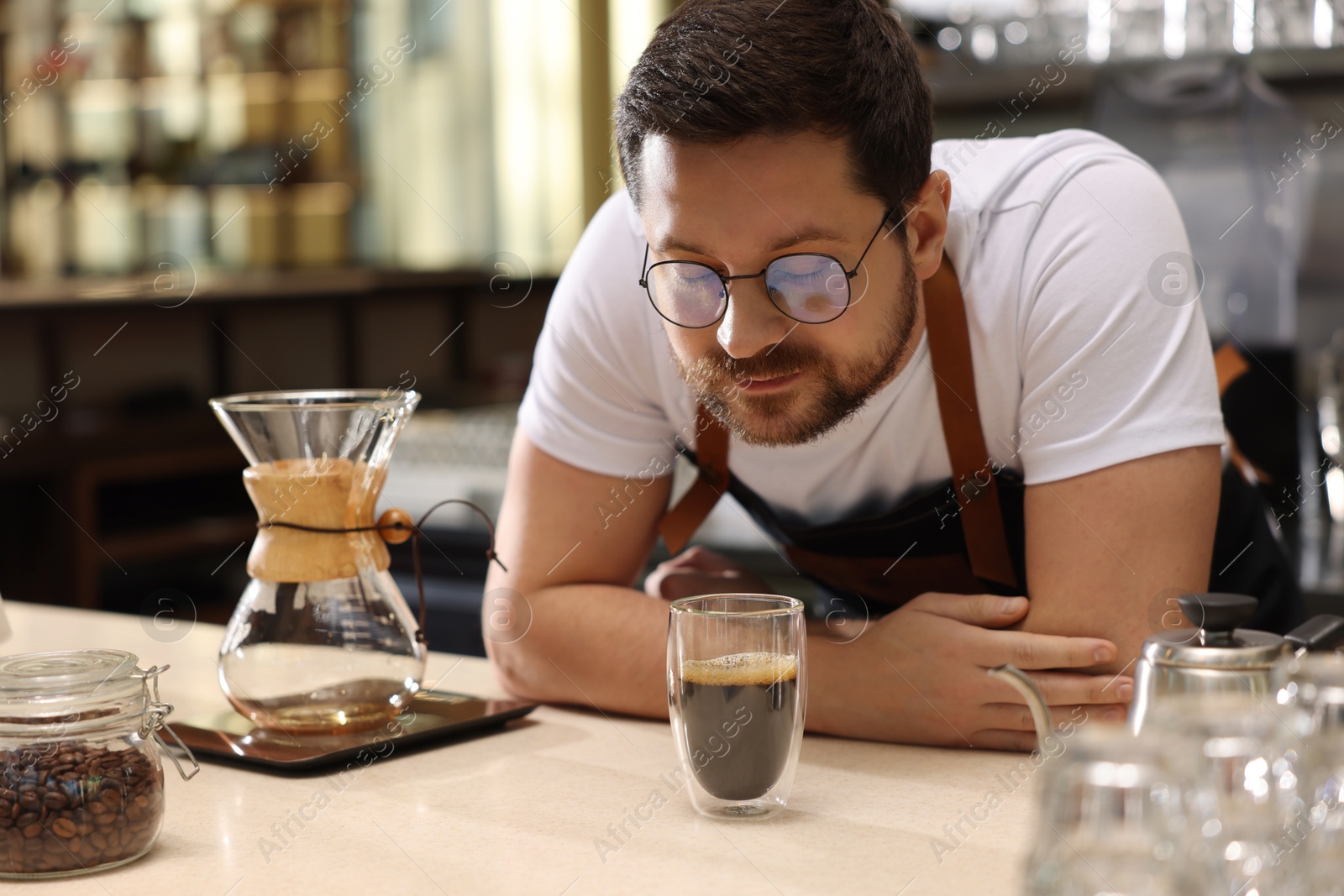 Photo of Barista sniffing aromatic filter coffee at table in cafe