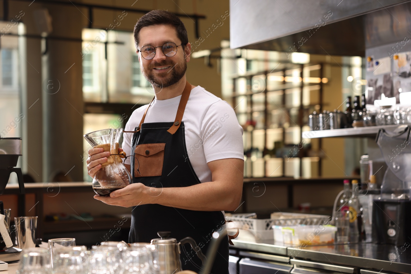 Photo of Barista with glass coffeemaker at table in cafe