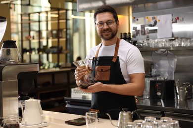 Photo of Barista with glass coffeemaker at table in cafe