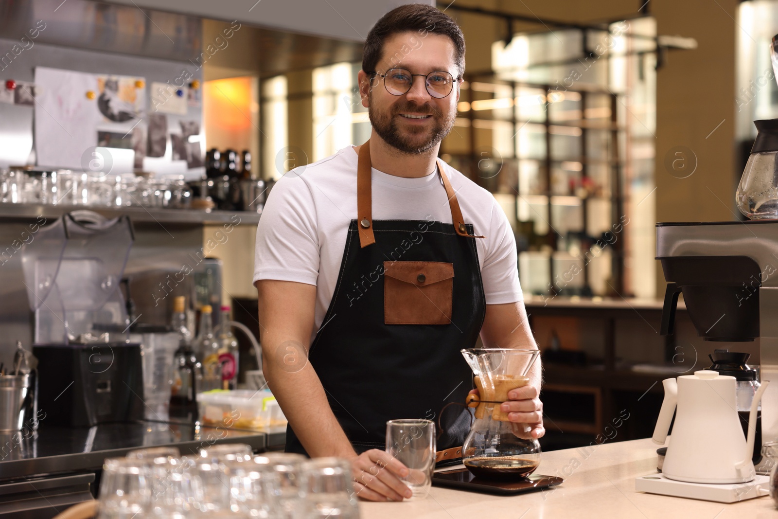 Photo of Barista with glass coffeemaker at table in cafe