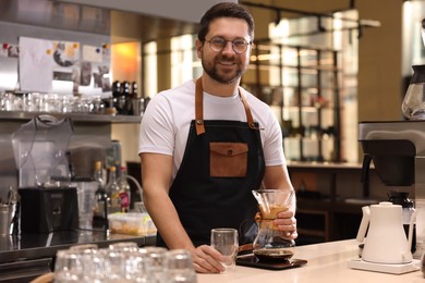 Photo of Barista with glass coffeemaker at table in cafe