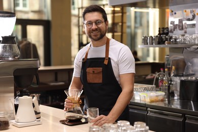 Photo of Barista with glass coffeemaker at table in cafe