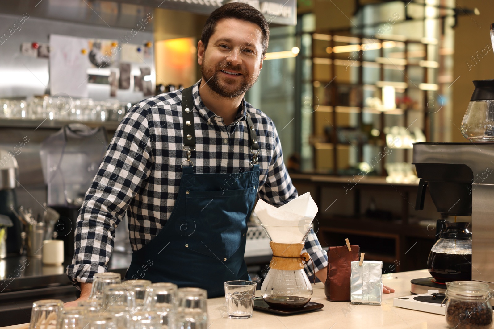 Photo of Barista with glass coffeemaker at table in cafe