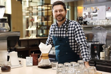 Photo of Barista with glass coffeemaker at table in cafe