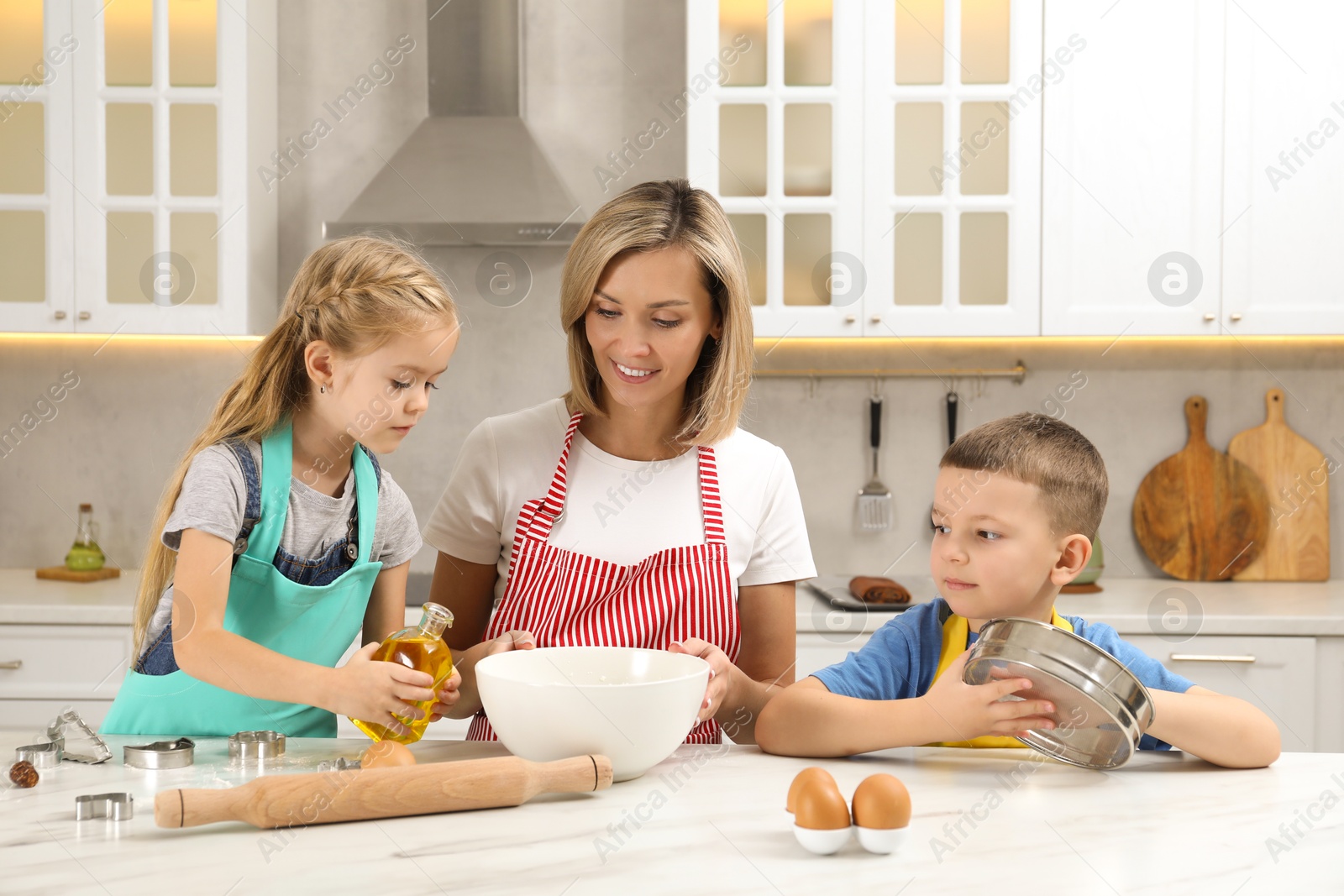 Photo of Children helping their mom making cookies in kitchen at home