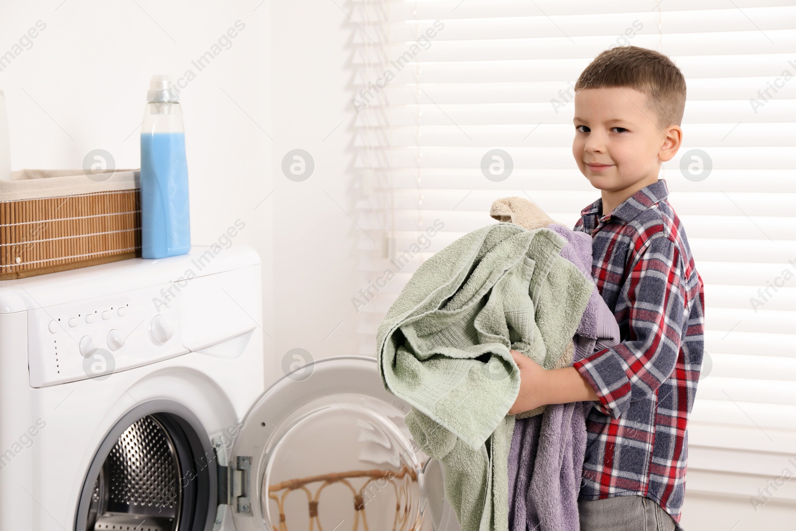 Photo of Little helper. Cute boy doing laundry at home