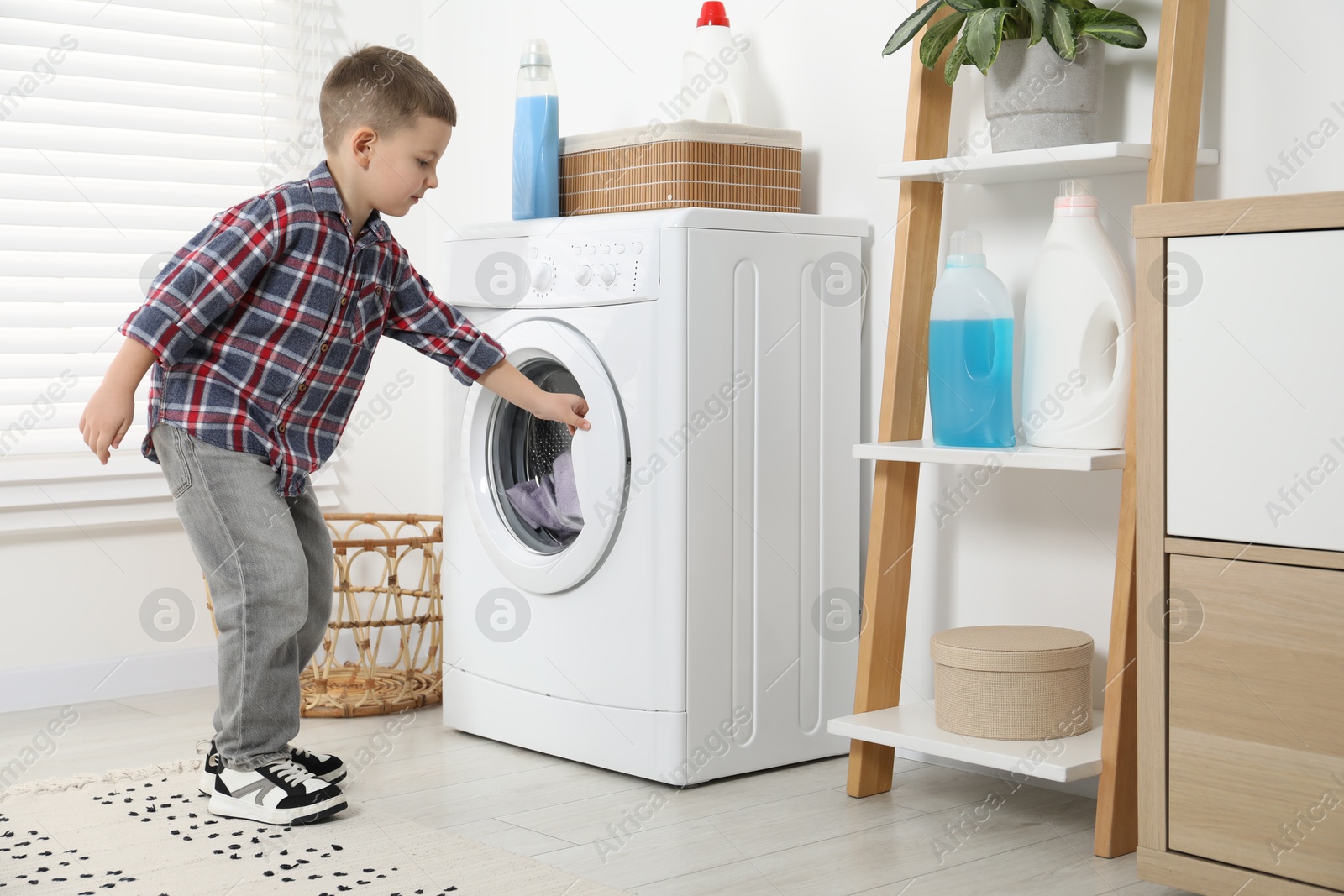 Photo of Little helper. Cute boy doing laundry at home