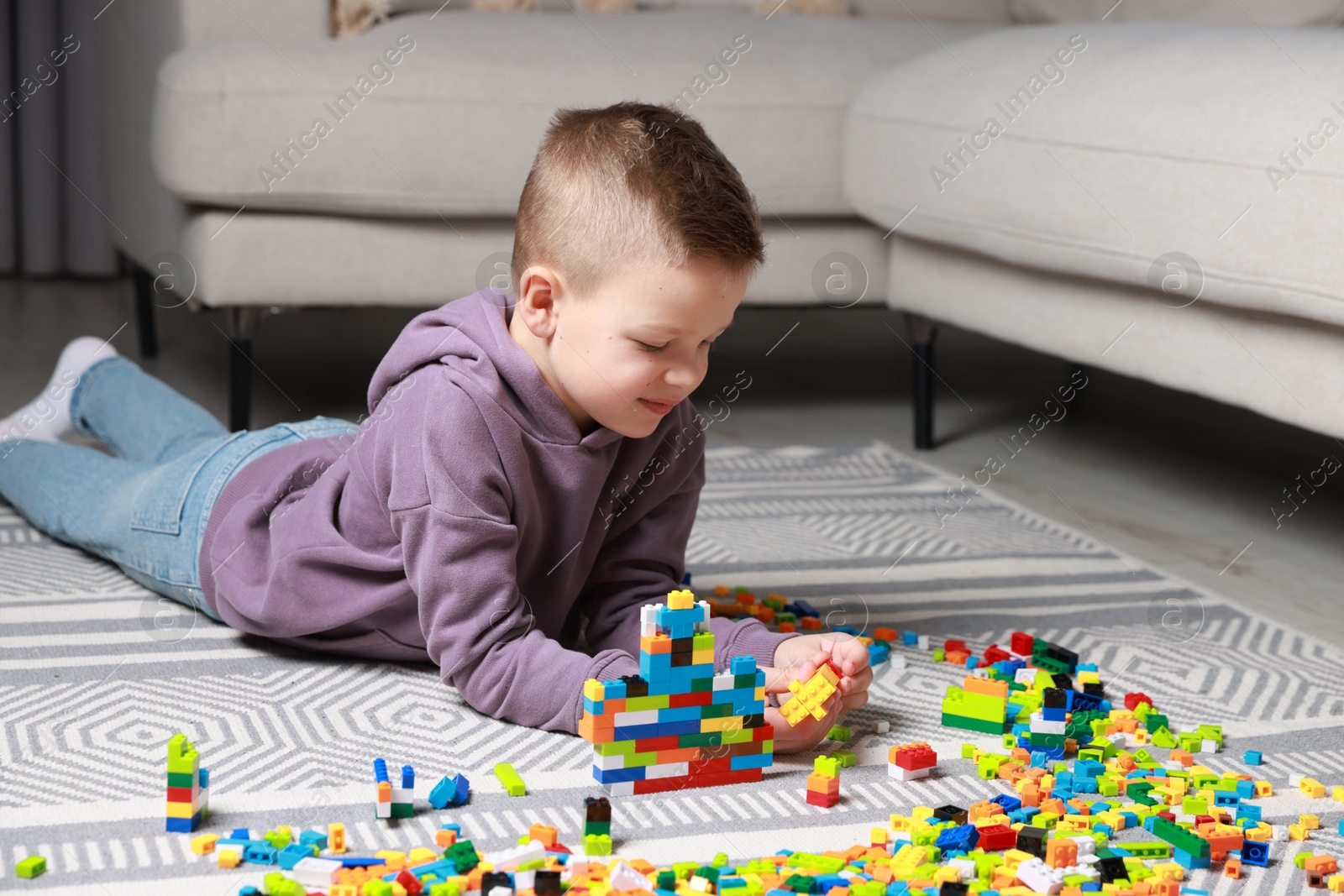 Photo of Cute boy playing with building blocks on floor at home. Space for text