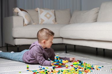 Cute boy playing with building blocks on floor at home. Space for text