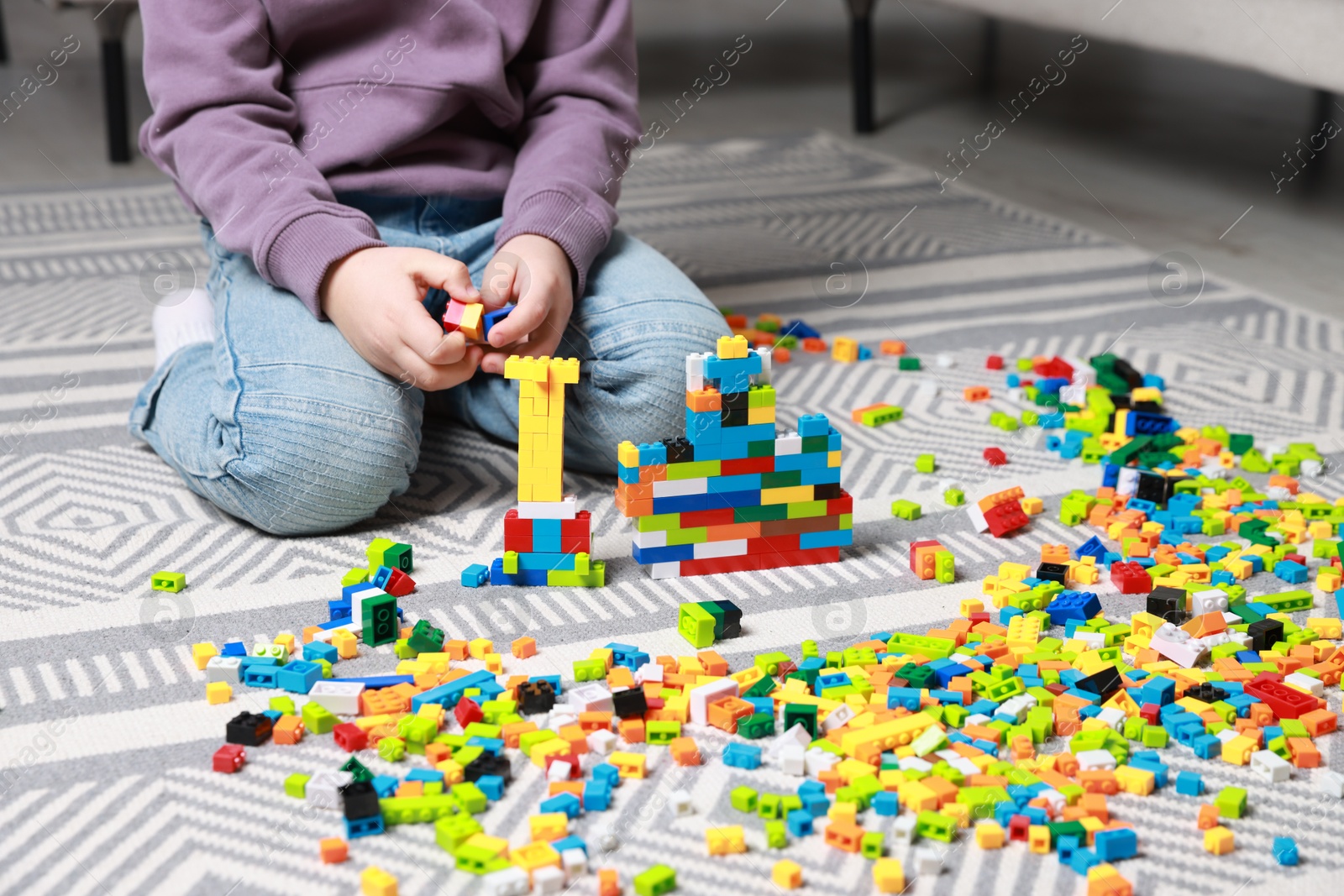 Photo of Cute boy playing with building blocks on floor at home, closeup