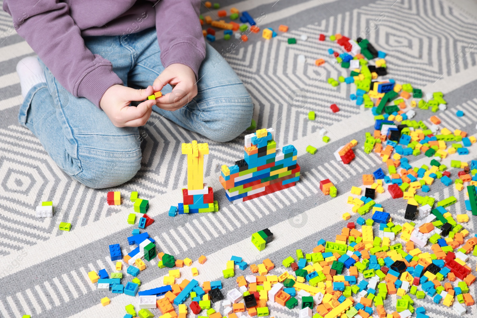 Photo of Cute boy playing with building blocks on floor at home, closeup