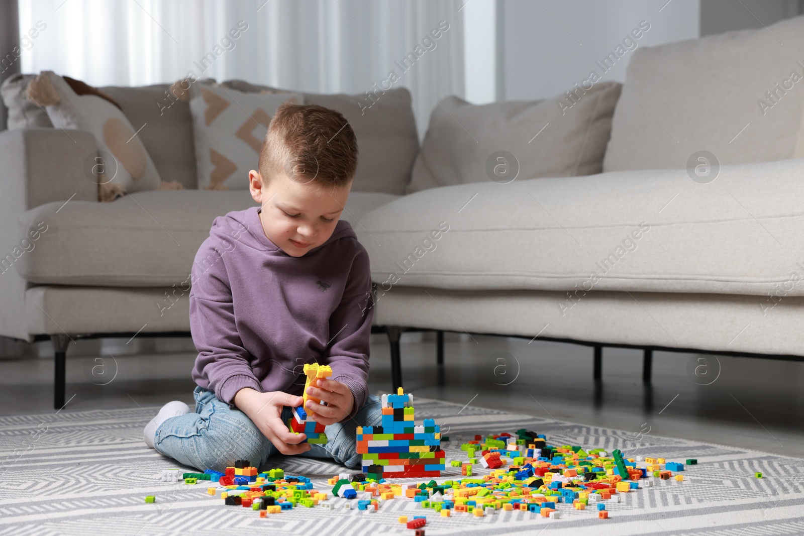 Photo of Cute boy playing with building blocks on floor at home. Space for text