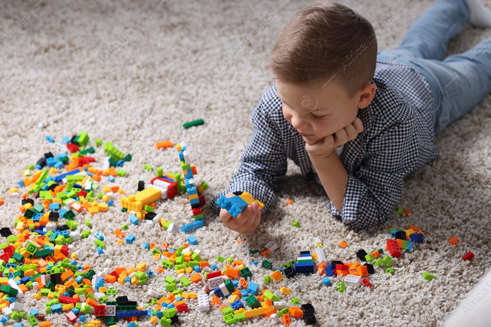 Photo of Cute boy playing with building blocks on floor at home