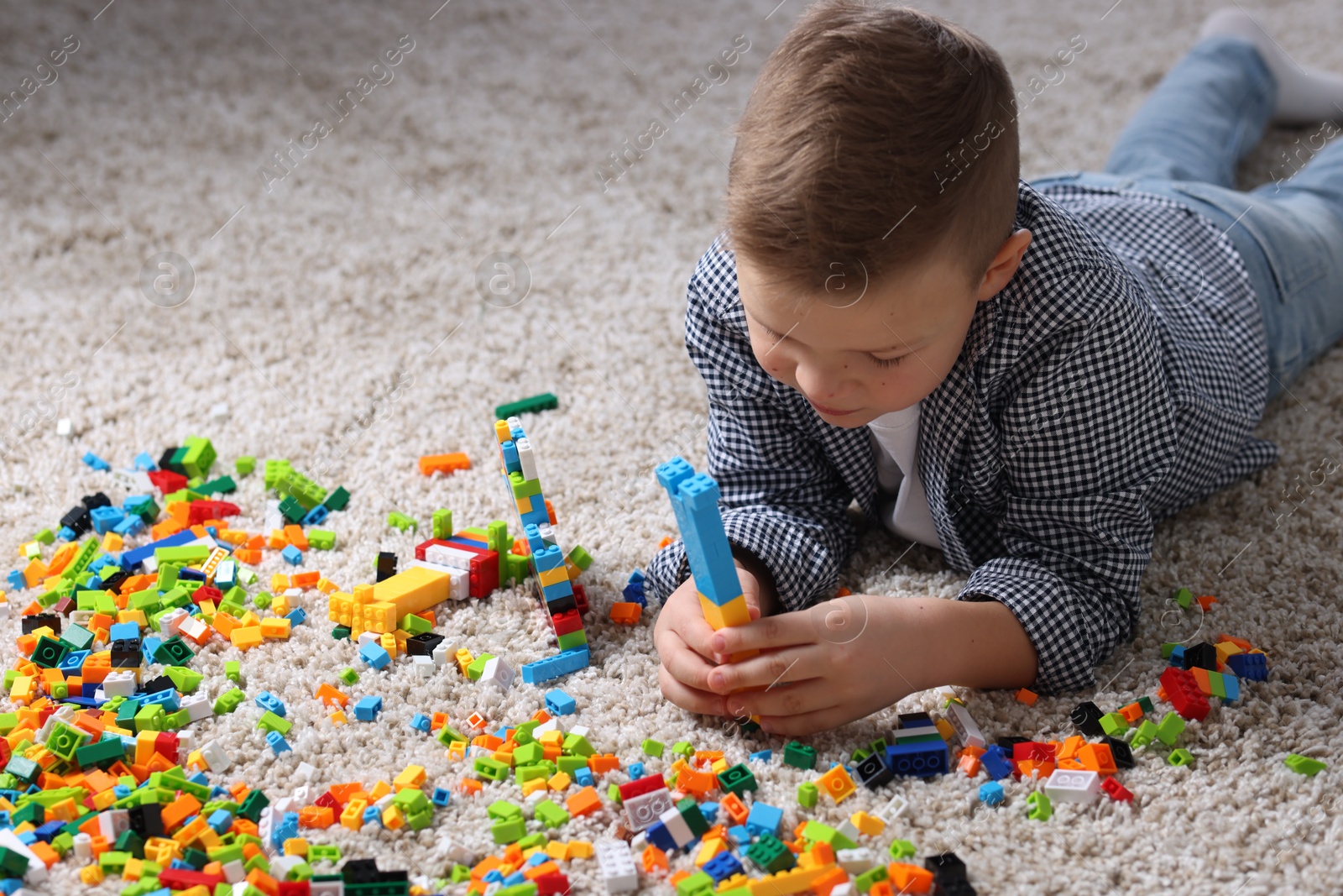 Photo of Cute boy playing with building blocks on floor at home