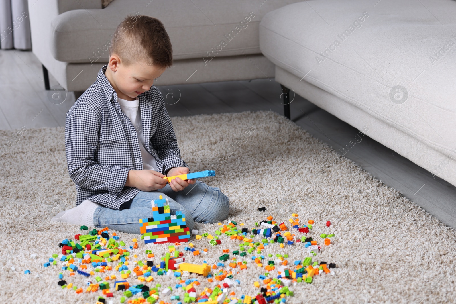 Photo of Cute boy playing with building blocks on floor at home. Space for text