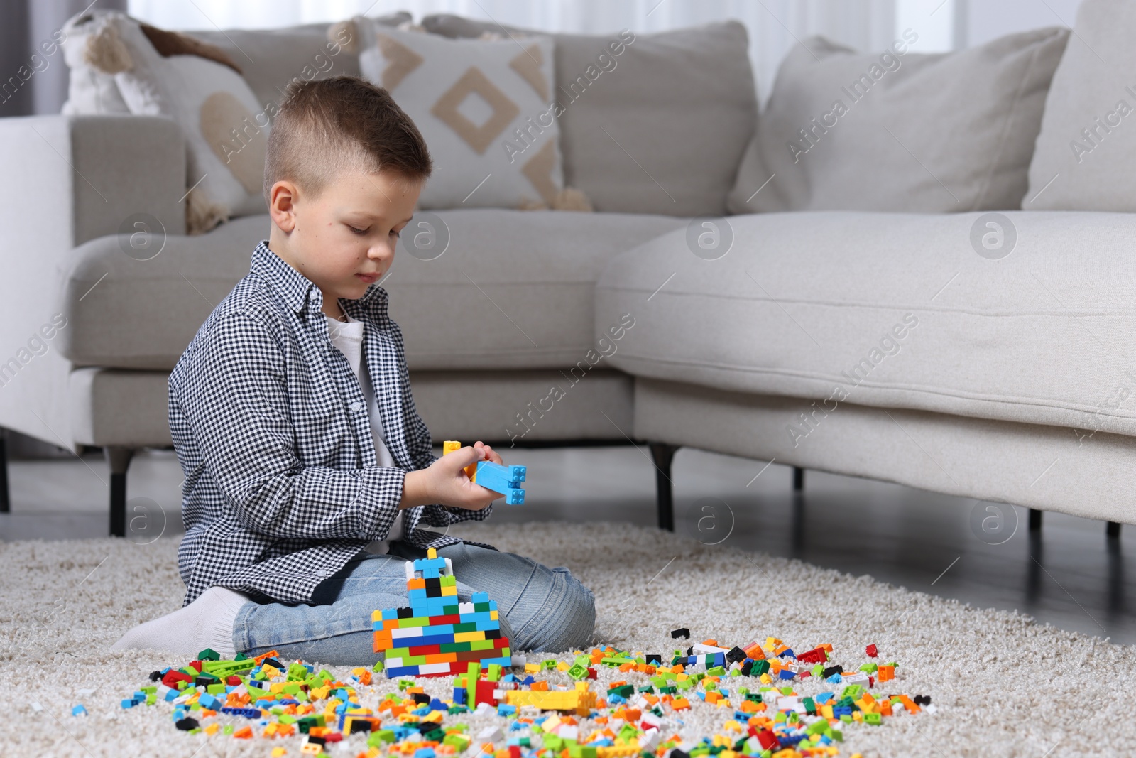 Photo of Cute boy playing with building blocks on floor at home. Space for text