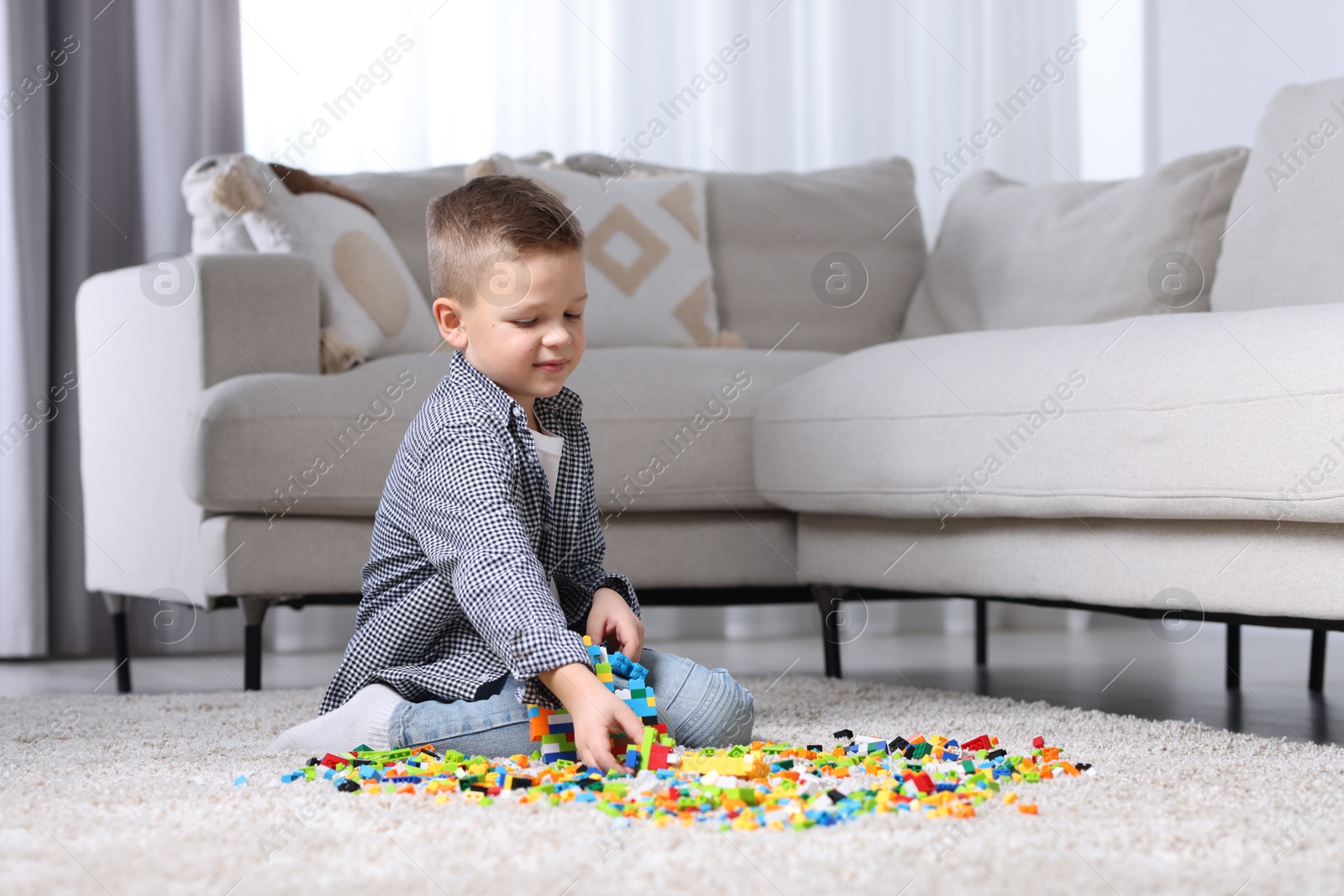 Photo of Cute boy playing with building blocks on floor at home. Space for text