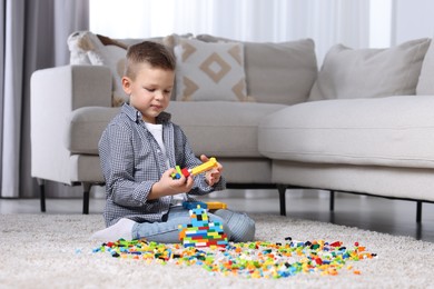 Cute boy playing with building blocks on floor at home. Space for text