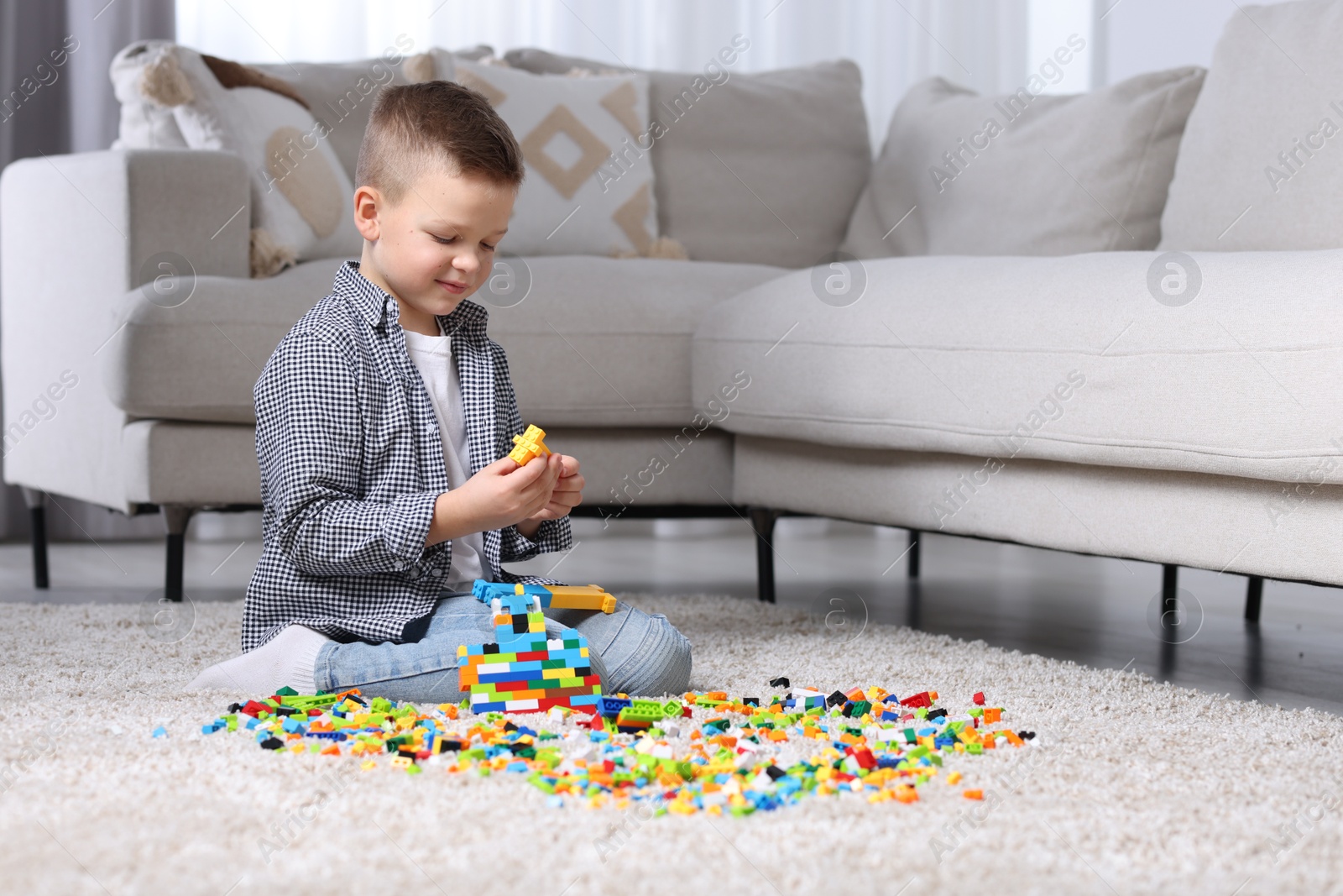 Photo of Cute boy playing with building blocks on floor at home. Space for text