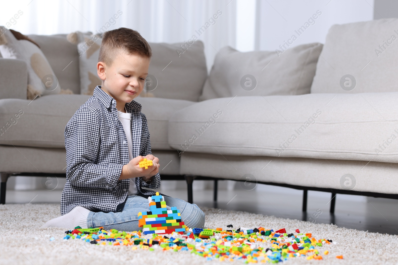 Photo of Cute boy playing with building blocks on floor at home. Space for text