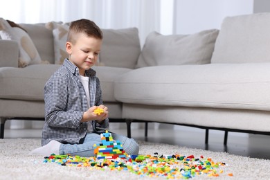 Cute boy playing with building blocks on floor at home. Space for text