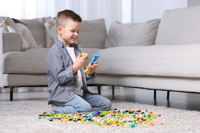 Photo of Cute boy playing with building blocks on floor at home. Space for text