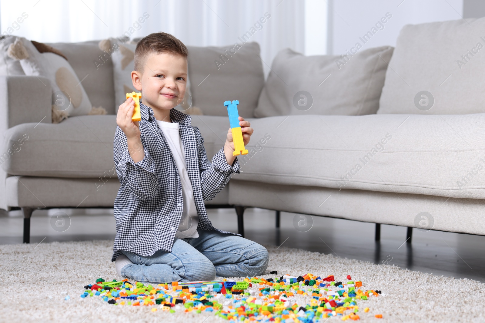 Photo of Cute boy playing with building blocks on floor at home. Space for text