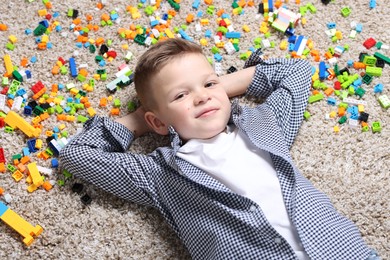 Cute boy and colorful building blocks on floor, top view