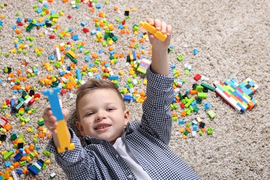 Cute boy and colorful building blocks on floor, top view