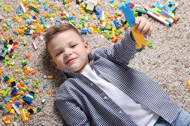 Cute boy and colorful building blocks on floor, top view