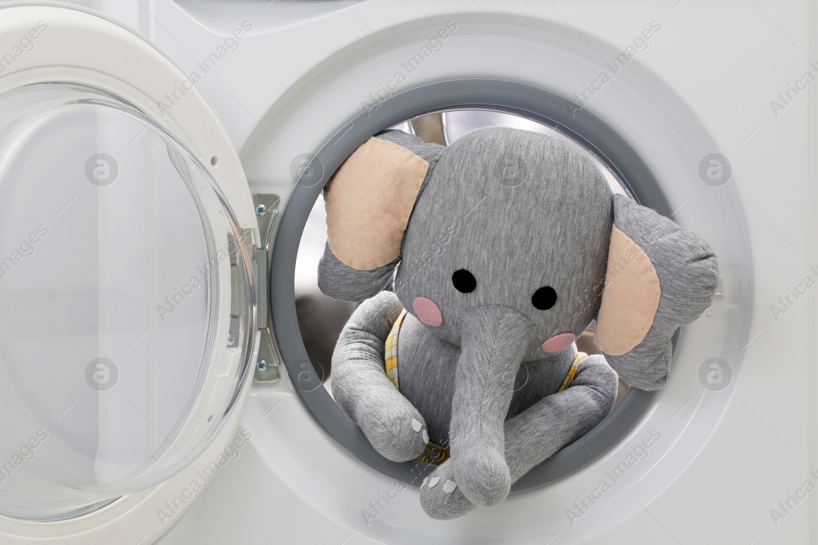 Photo of Washing machine with toy elephant as background, closeup