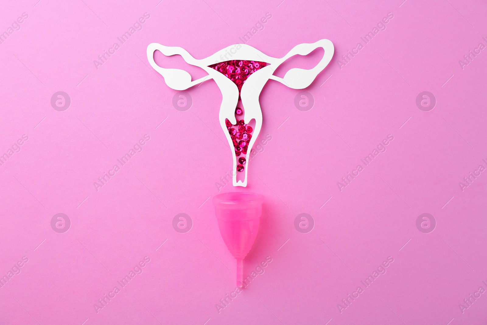 Photo of Paper uterus with sequins and menstrual cup on violet background, top view