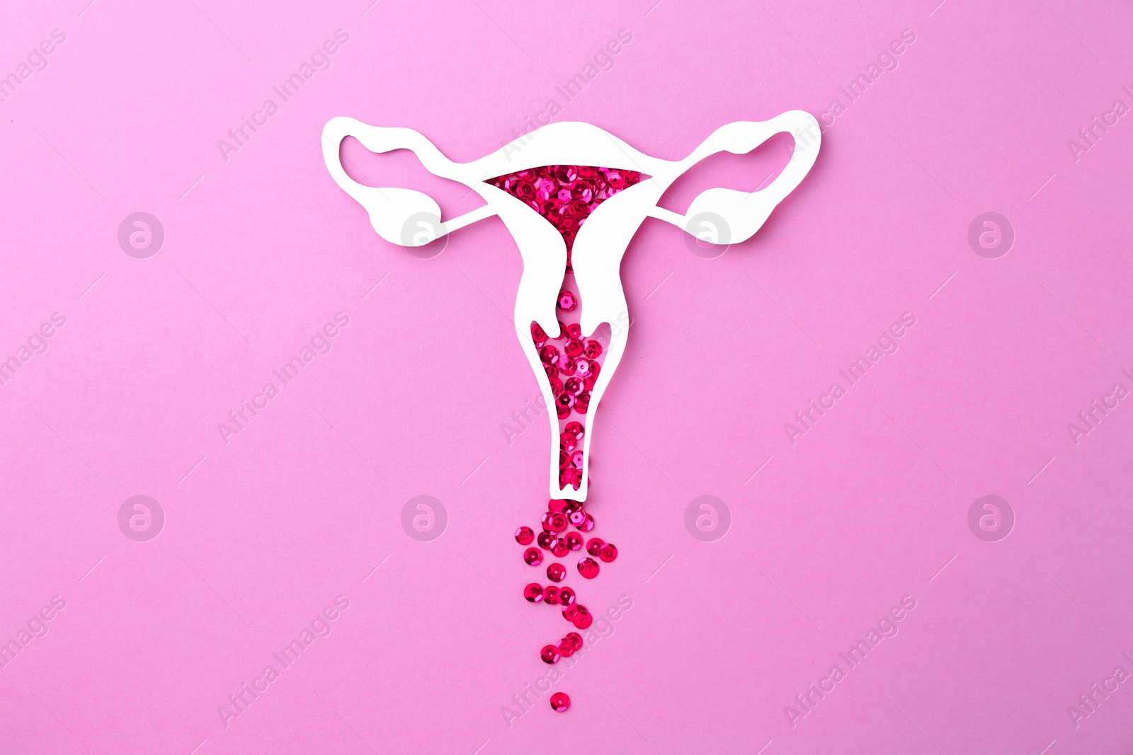 Photo of Menstruation. Paper uterus with sequins on violet background, top view