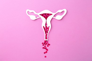 Photo of Menstruation. Paper uterus with sequins on violet background, top view