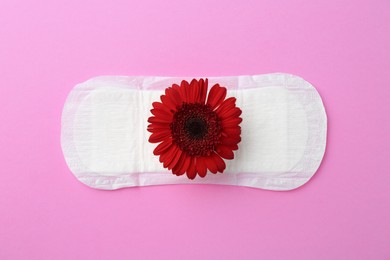 Photo of Menstrual pad with red flower on violet background, top view