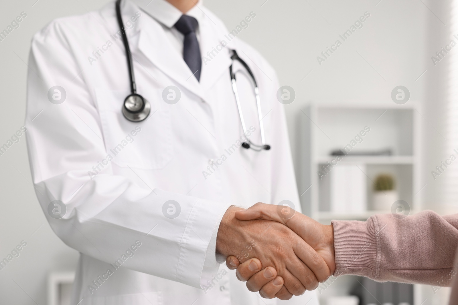 Photo of Doctor shaking hands with patient in hospital, closeup