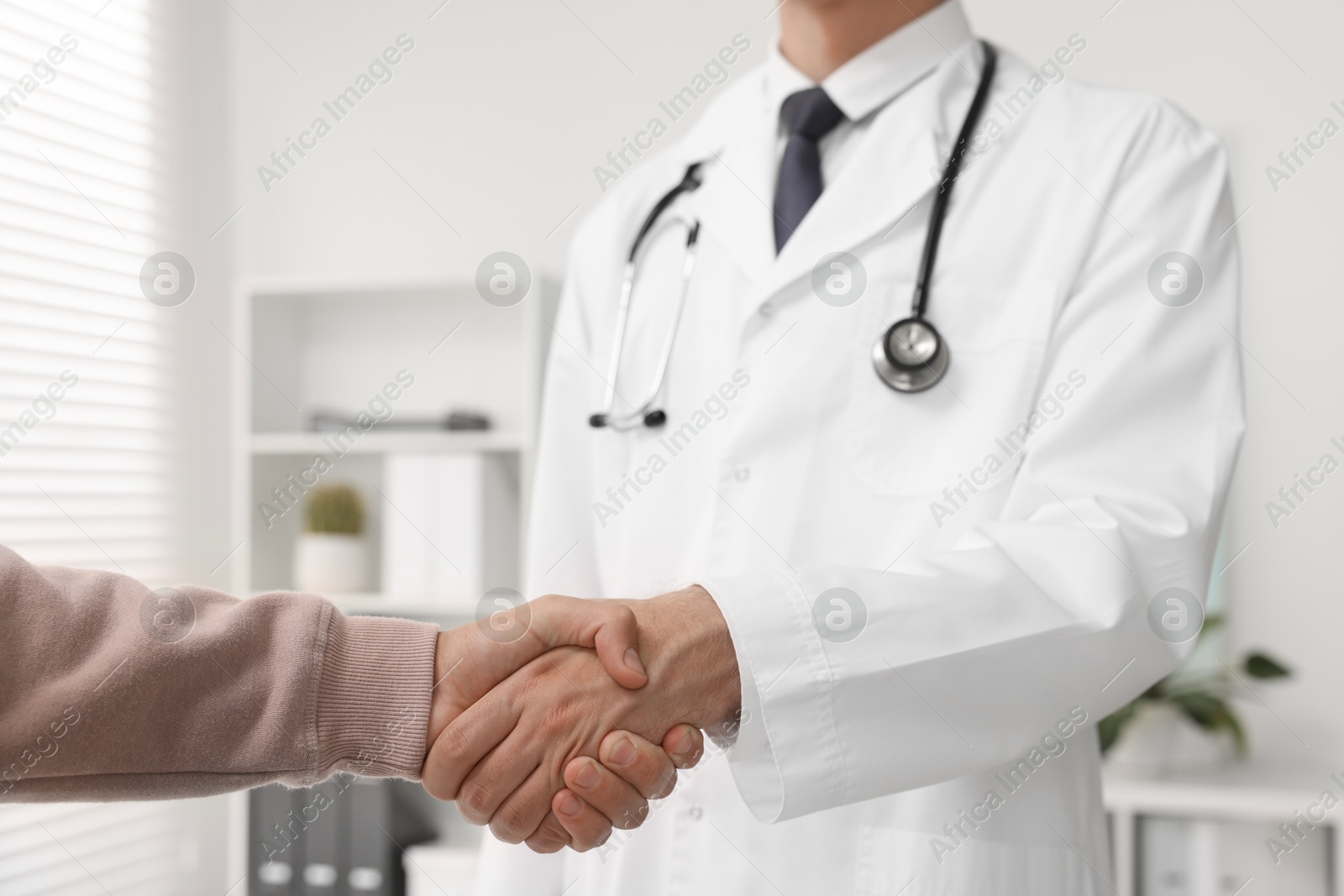 Photo of Doctor shaking hands with patient in hospital, closeup