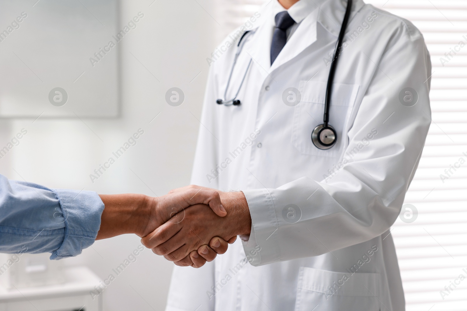 Photo of Doctor shaking hands with patient in hospital, closeup