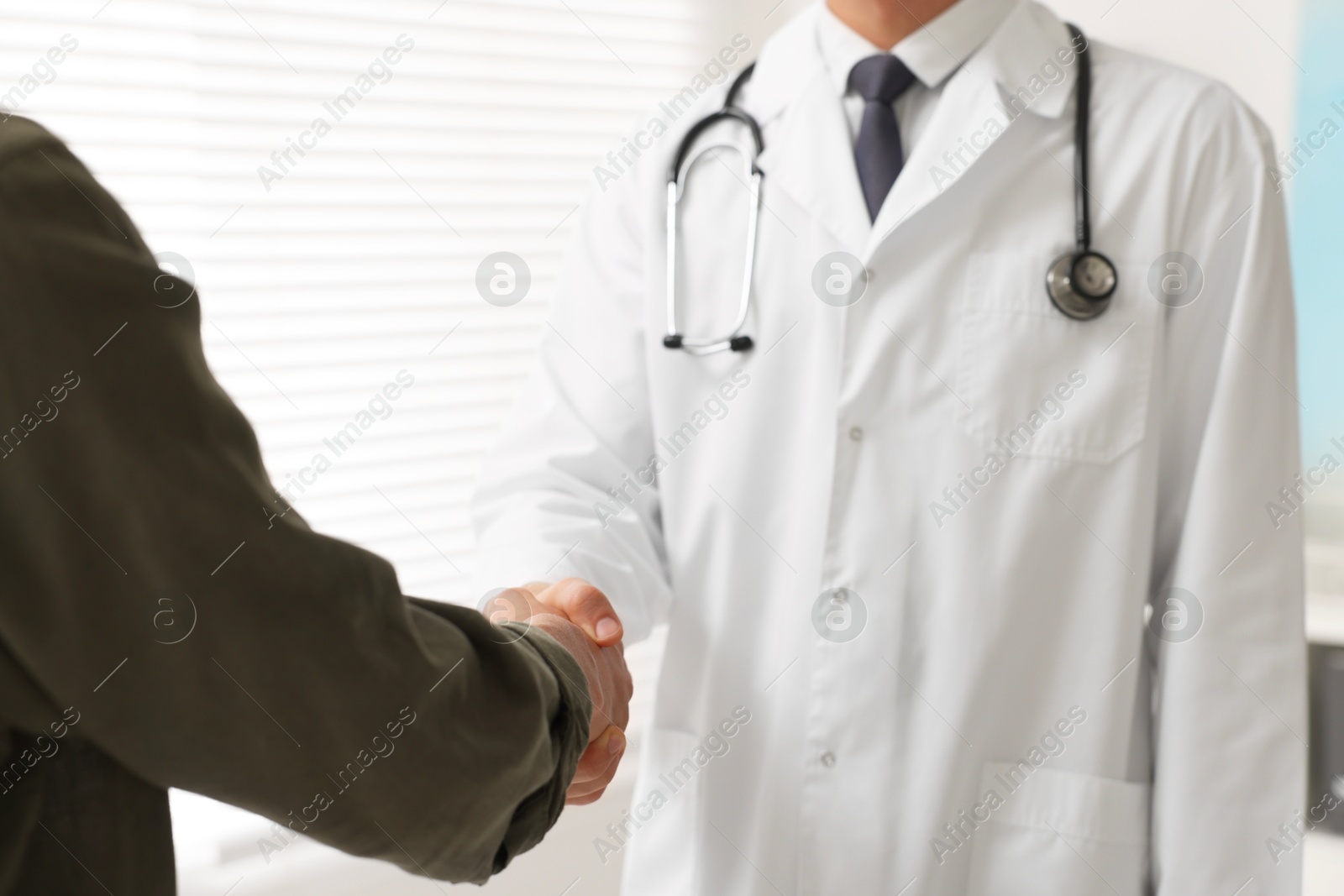 Photo of Doctor shaking hands with patient in hospital, closeup