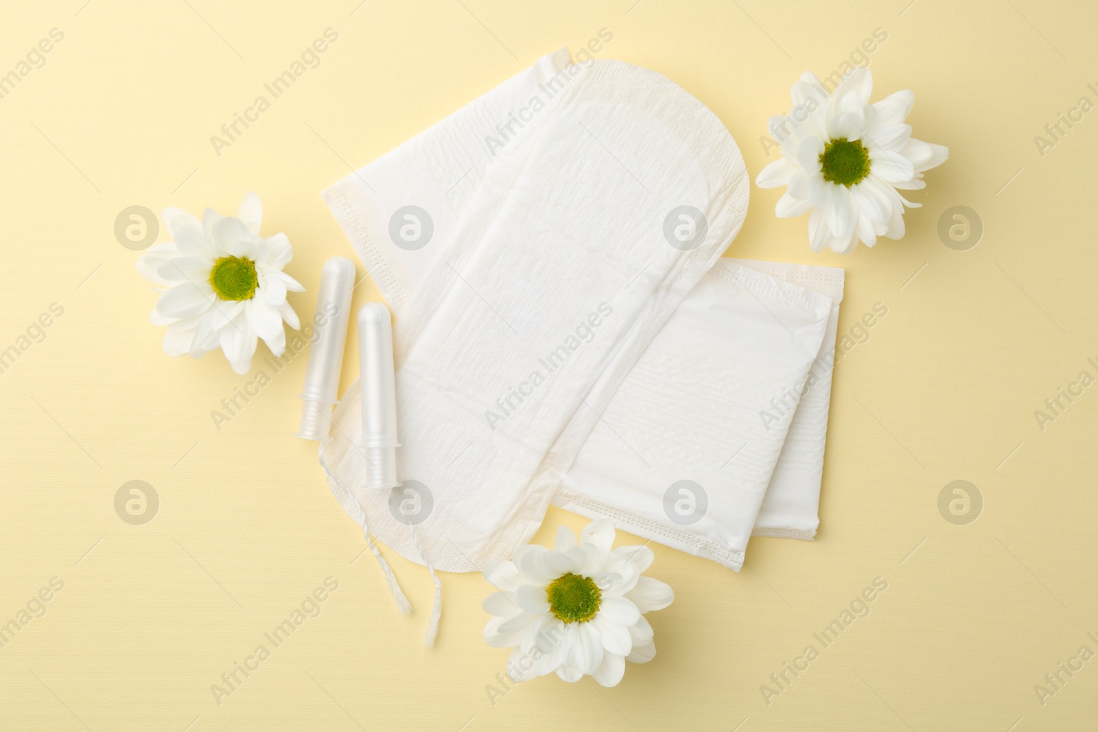 Photo of Menstrual pads, flowers and tampons on beige background, flat lay