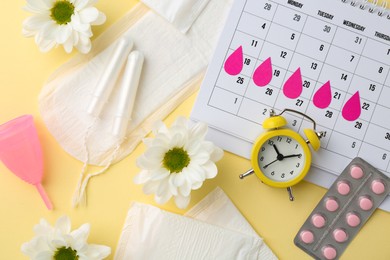 Photo of Flat lay composition with calendar and menstrual products on beige background