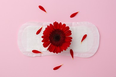 Photo of Menstrual pad with red flower on pink background, top view