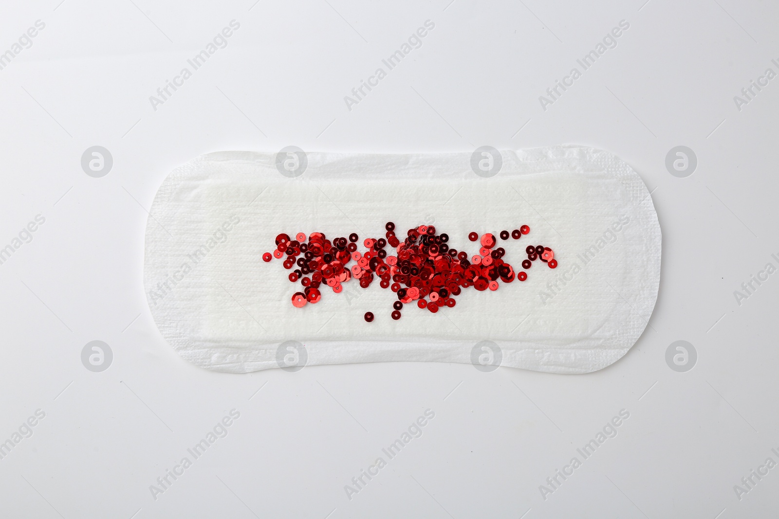 Photo of Menstrual pad with red sequins on white background, top view