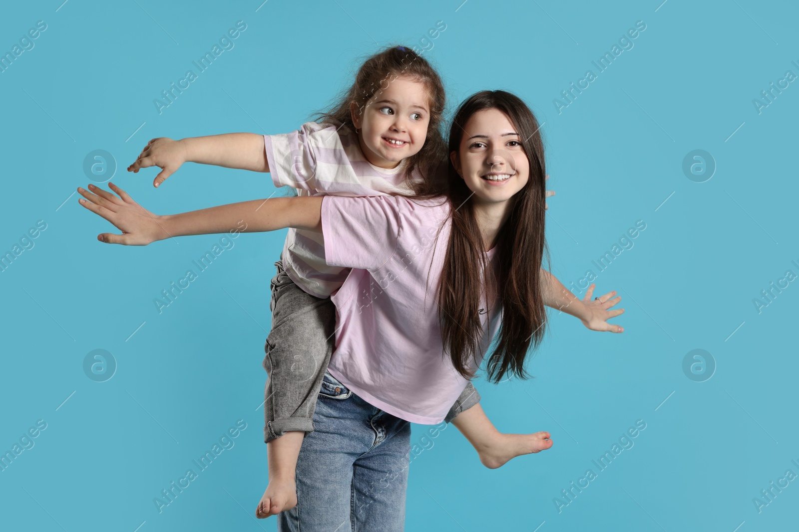 Photo of Portrait of cute sisters on light blue background