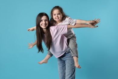 Photo of Portrait of cute sisters on light blue background