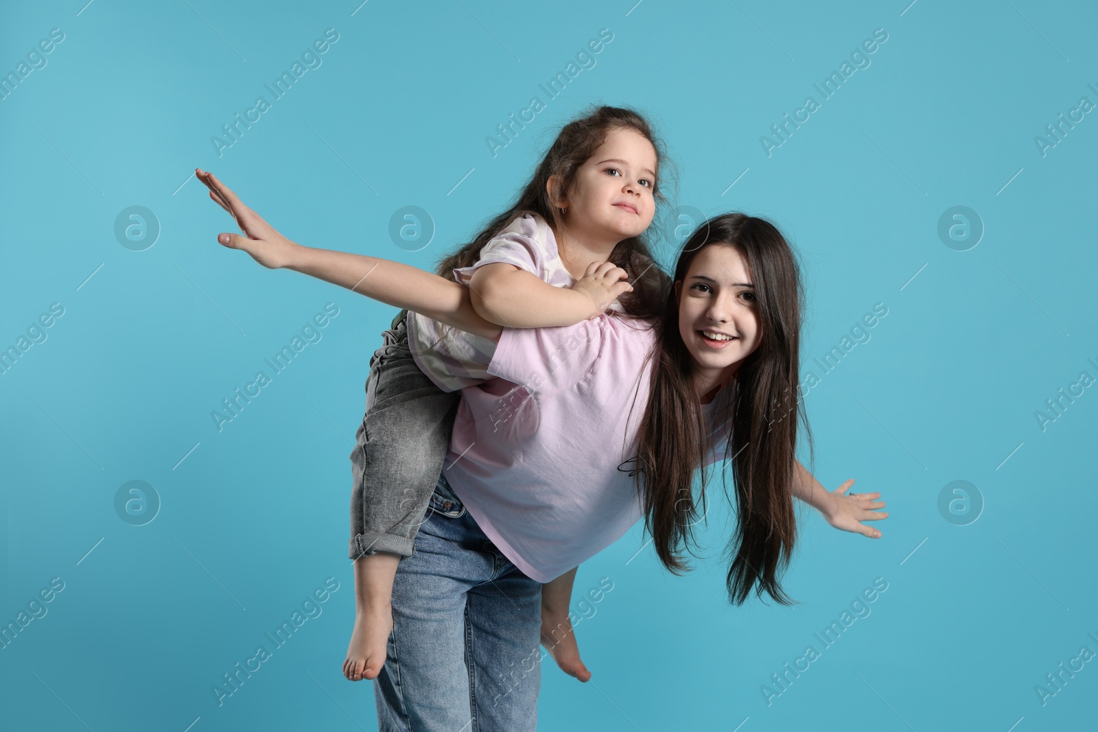 Photo of Portrait of cute sisters on light blue background